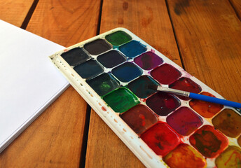 Multicolored palette of watercolor paints with brushes. Art, drawing.