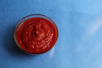 red tomato sauce in a glass saucepan on a blue blue background with space for the text kitchen cafe restaurant