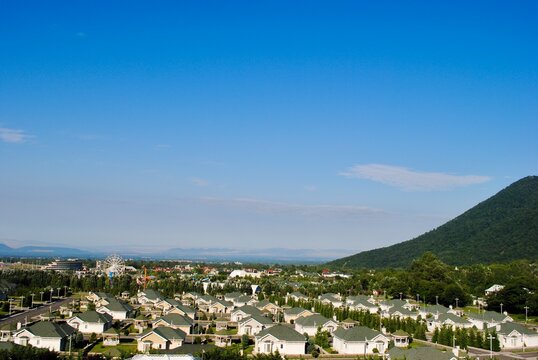A distant view of a land/city scape of a new urban town at the foot of Caucasus mountain range against blue sky. Gebele Gabala Azerbaijan