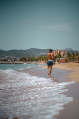 One skimboarder walking on the shore in order to catch some waves at Can Pere Antoni beach (Palma de Mallorca, Spain)