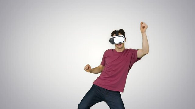 Advanced gamer in casual outfit playing dancing game in VG headset on gradient background.
