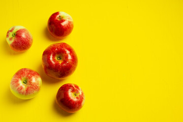 Red ripe apples on a yellow background. Copy space. Top view