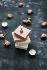 Homemade floral soap. Natural soap and rose flowers on dark background. Spa concept, body care products. Flat lay, top view