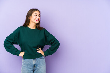 Young caucasian woman isolated on purple background confident keeping hands on hips.