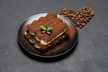 Obraz na płótnie Canvas portion of Classic tiramisu dessert on ceramic plate and heart shaped coffee beans on concrete background