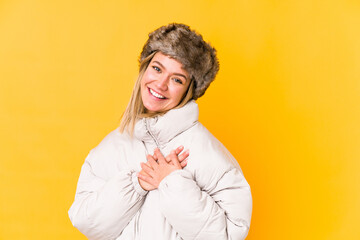 Young caucasian woman wearing a winter clothes isolated has friendly expression, pressing palm to chest. Love concept.