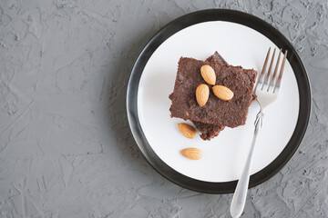 Serving of homemade chocolate brownie with almond nuts, top view. Traditional fudgy cake