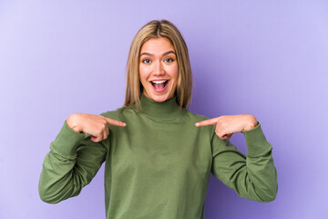 Young blonde caucasian woman isolated surprised pointing with finger, smiling broadly.