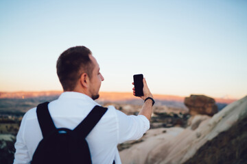 Man with backpack posing for taking selfie in open air