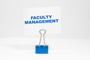 FACULTY MANAGEMENT nscription on a white business card on a white endless background in a blue clip.
