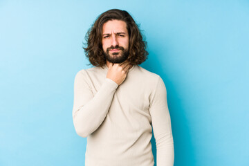 Young long hair man isolated on a blue background suffers pain in throat due a virus or infection.