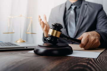 Justice and law concept.Male judge in a courtroom with the gavel, working with, computer and docking keyboard, eyeglasses, on table in morning light