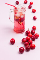 Refreshing summer apple drink with ice in glass. Small red apples on white