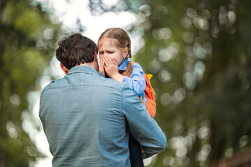Dad calms his daughter, holding her in his arms. the girl is upset and crying