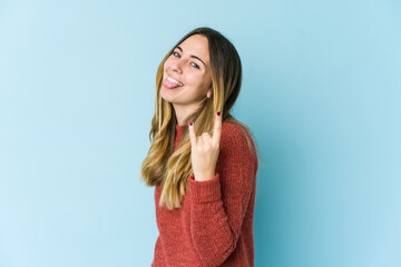 Fototapeta premium Young caucasian woman isolated on blue background showing rock gesture with fingers