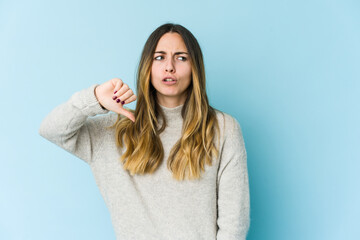 Fototapeta premium Young caucasian woman isolated on blue background showing thumb down and expressing dislike.
