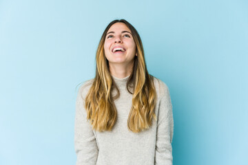 Obraz premium Young caucasian woman isolated on blue background relaxed and happy laughing, neck stretched showing teeth.