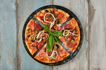 Supreme mixed pizza from top view on wooden background.