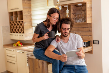 Couple drinking morning coffee and using tablet computer