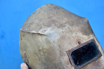 Protective welding shield in hand on a blue background