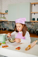 Girl in the kitchen kneads dough for glazed gingerbread