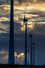 Windmills stately align the green energy makers of the future during a sunset.