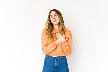 Young caucasian woman isolated on white background has friendly expression, pressing palm to chest. Love concept.