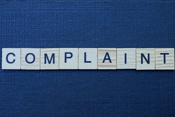 gray word complaint from small wooden letters on a black table