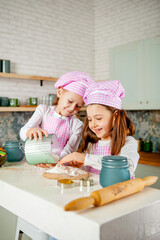 two girlfriends in the kitchen knead the dough and sprinkle flour