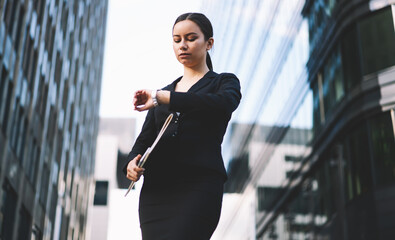 Focused on wristwatch stylish woman waiting meeting on street in downtown