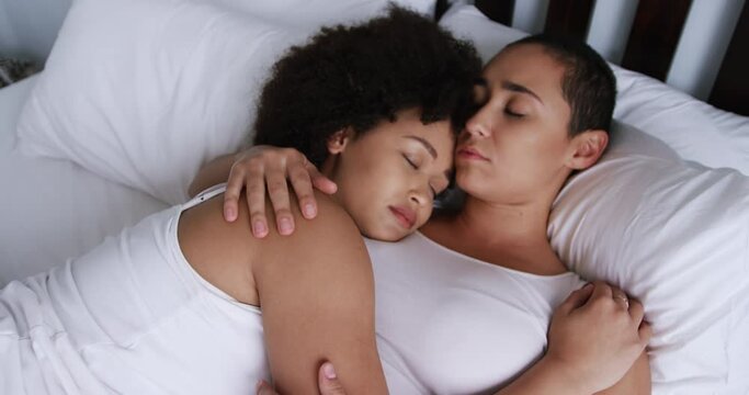 Lesbian couple sleeping on bed in bedroom
