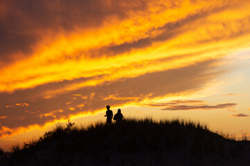 Obraz na płótnie Canvas Silhouette of two people on a hill viewing a sunset