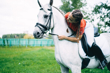 Female jockey leaning toward horses neck