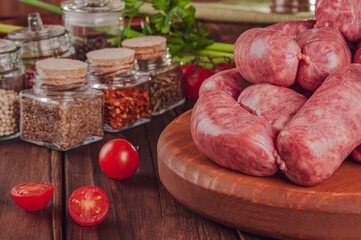 Raw brazilian sausages on the wooden board with ingredients - Linguiça toscana