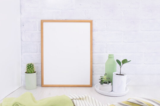 Empty picture mockup with wooden frame on white brick wall background with succulents plants and green vase. Light interior
