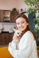 young smiling girl hugs a chihuahua tightly