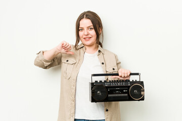 Young curvy woman holding a retro radio feels proud and self confident, example to follow.