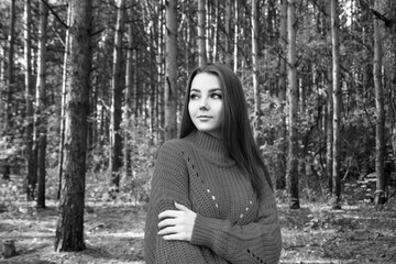 Young woman posing in the red sweater among trees.