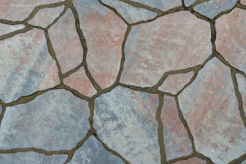 Floor made of different size reddish and blueish stones with cement grout. Ground floor layered with stone tiles