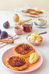 Homemade puff pastry fig tarts with vanilla and honey mascarpone - Gordon Ramsey recipe. White wooden table background.