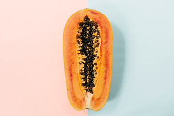Papaya on a pastel pink blue background, creative food concept, tropical fruit. Flat lay. Top view. Tropical travel, exotic fruit. Vegan and vegetarian concept