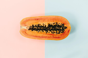 Papaya on a pastel pink blue background, creative food concept, tropical fruit. Flat lay. Top view. Tropical travel, exotic fruit. Vegan and vegetarian concept