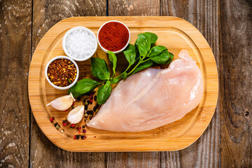 Fresh raw chicken fillet on wooden cutting board on wooden table