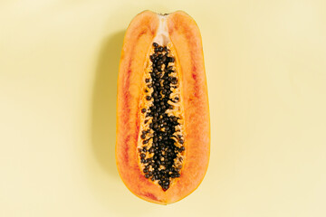 Papaya on a pastel yellow background, creative food concept, tropical fruit. Flat lay. Top view. Tropical travel, exotic fruit. Vegan and vegetarian concept
