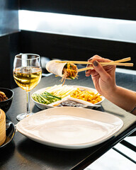 Asian cuisine and food in restaurant with hands and white wine 