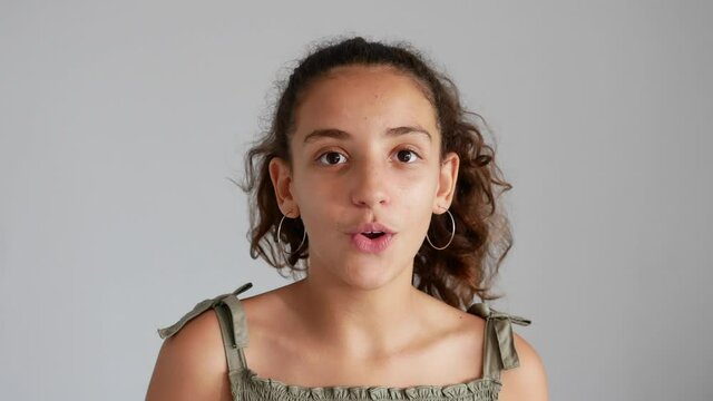 Teenage girl talking to the camera, isolated on gray background