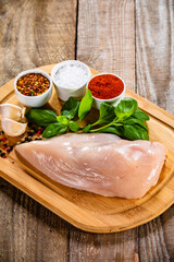 Fresh raw chicken fillet on wooden cutting board on wooden table