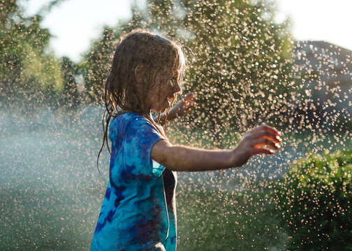 Little girl playing in the sprinklers