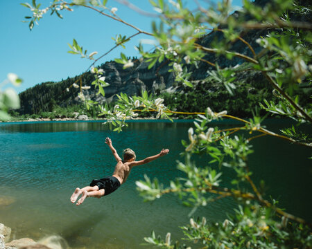 Boy jumping into a mountain lake