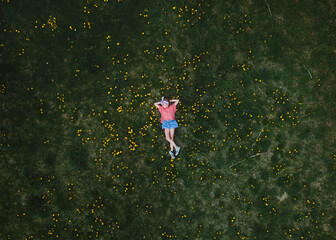 Ariel view of a child laying in the grass with dandelions 